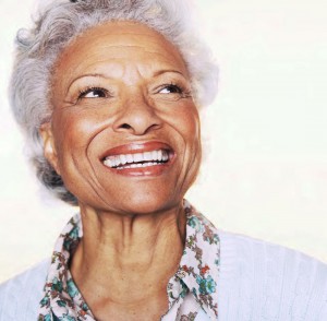 Elderly black woman with grey hair smiling. Alzheimer’s disease has a disparate impact on women.