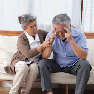 Elderly couple, husband holding his head, worried about Alzheimer's