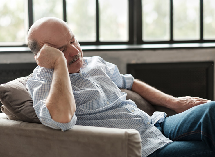 Senior man taking a nap on his couch at home