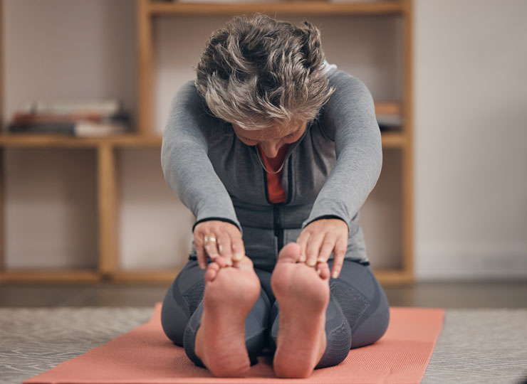 Elderly woman, yoga stretching and home on floor for wellness, overall health and brain health