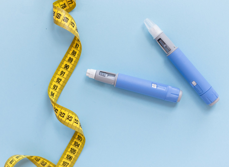 Close-up of packaged prescription medication and syringe on a wooden table, representing GLP-1 weight loss and diabetes drugs.
